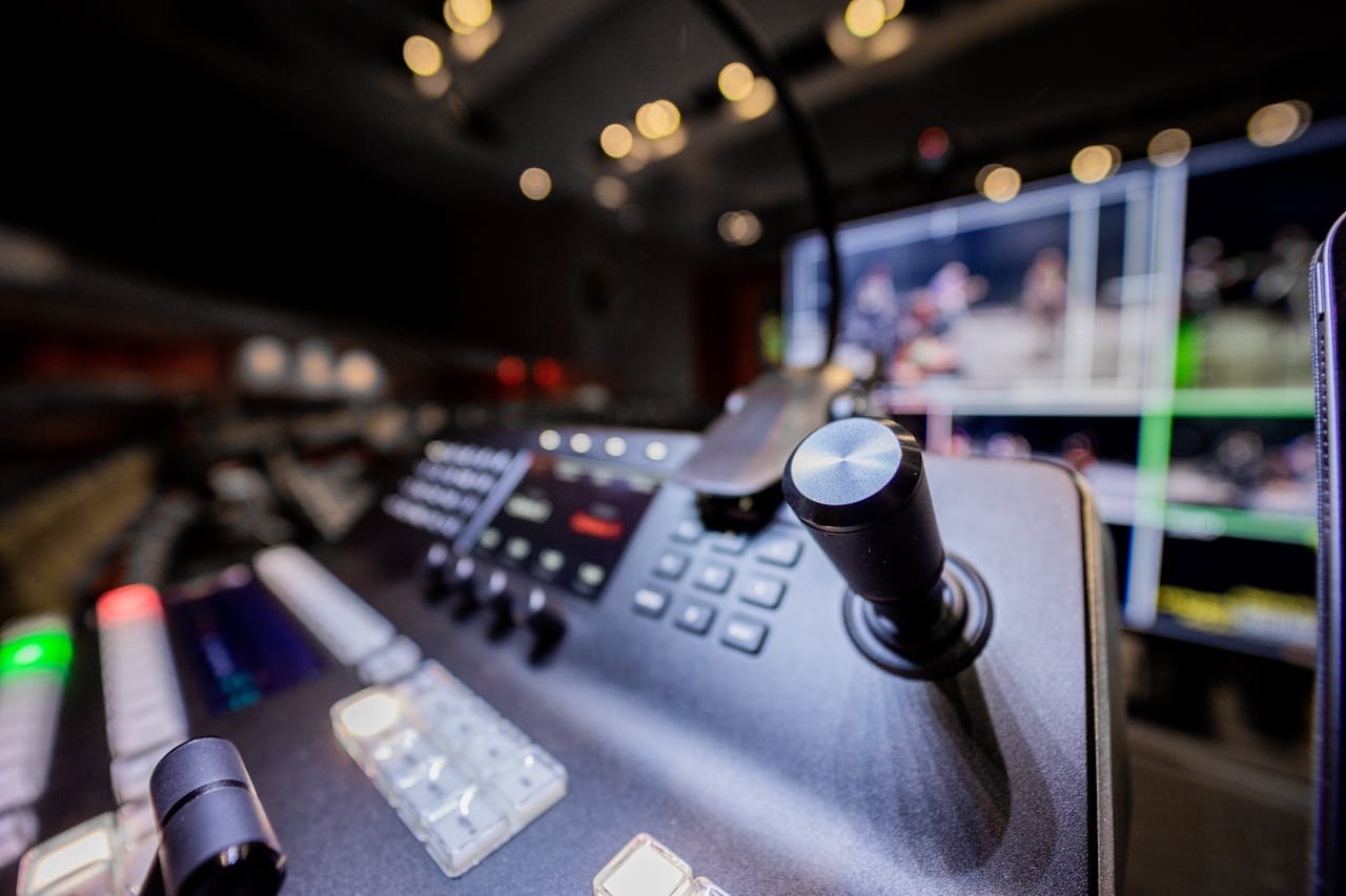 Closeup of modern professional audio console controller with buttons placed near screen in studio with lights